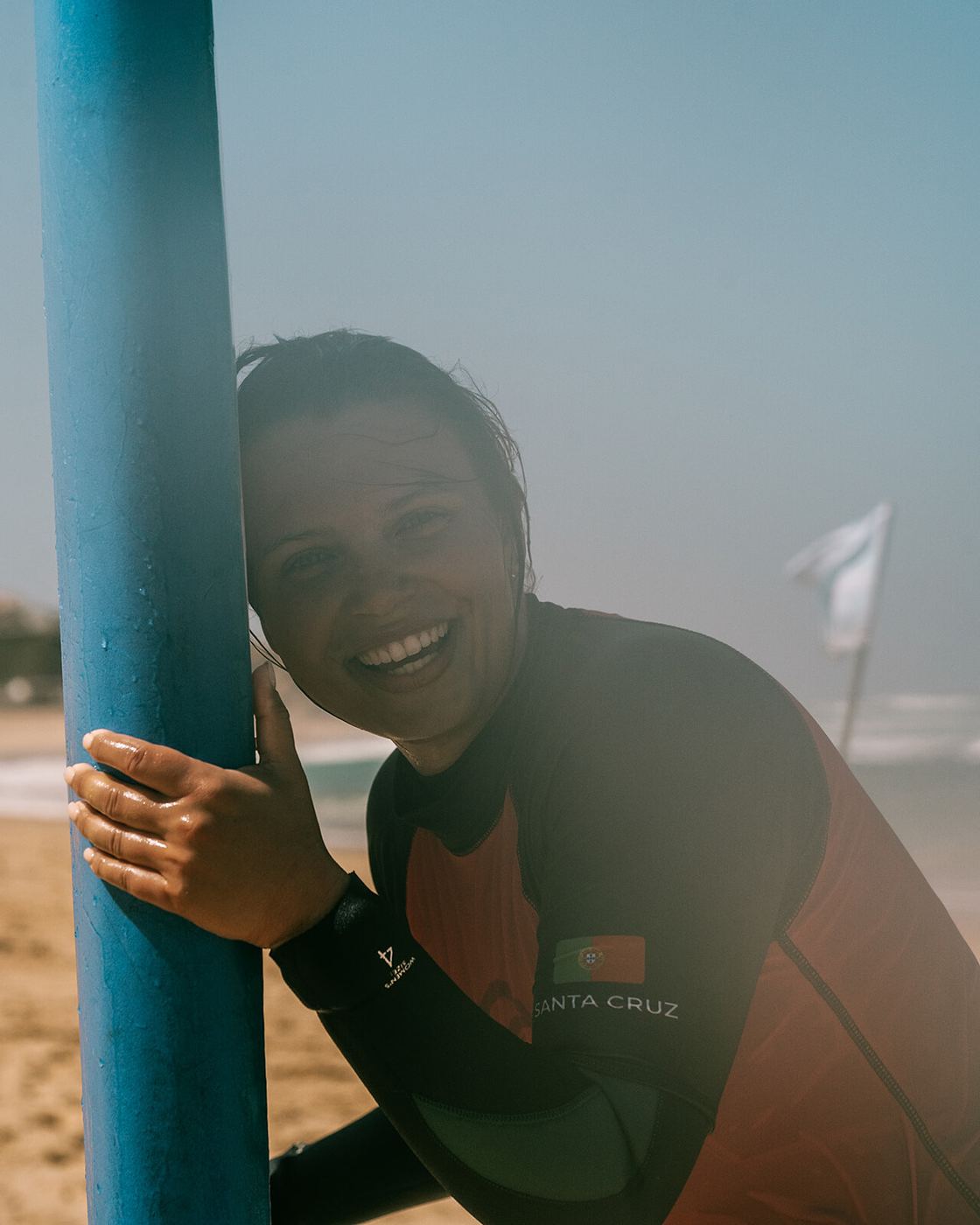 A surfer grinning behind her board