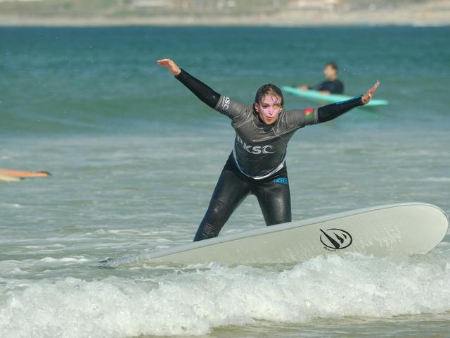 A surfer riding the whitewater in with her arms out