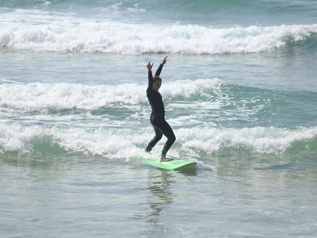 A surfer standing with her arms out on the way in