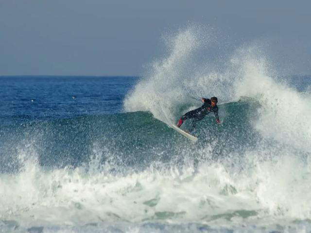 A surfer turning hard off the top of a wave