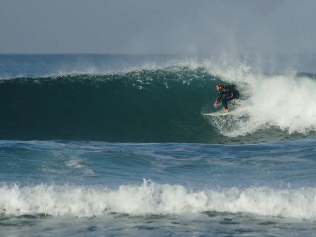 A surfer taking off on a steep, hollow one