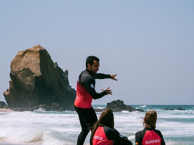 A Tsunami coach briefing the group on the sand before a lesson